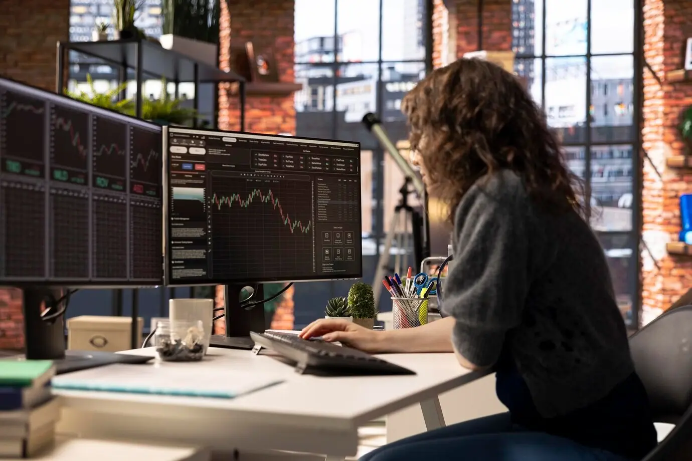 Una mujer joven estudia gráficos de negociación de acciones en su computadora.